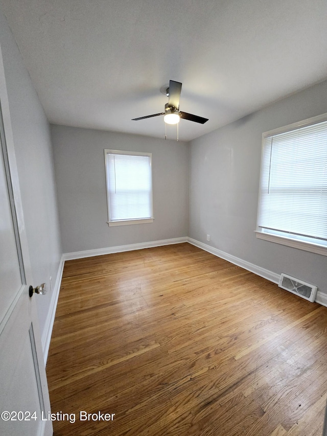 spare room with ceiling fan, a healthy amount of sunlight, and light hardwood / wood-style floors