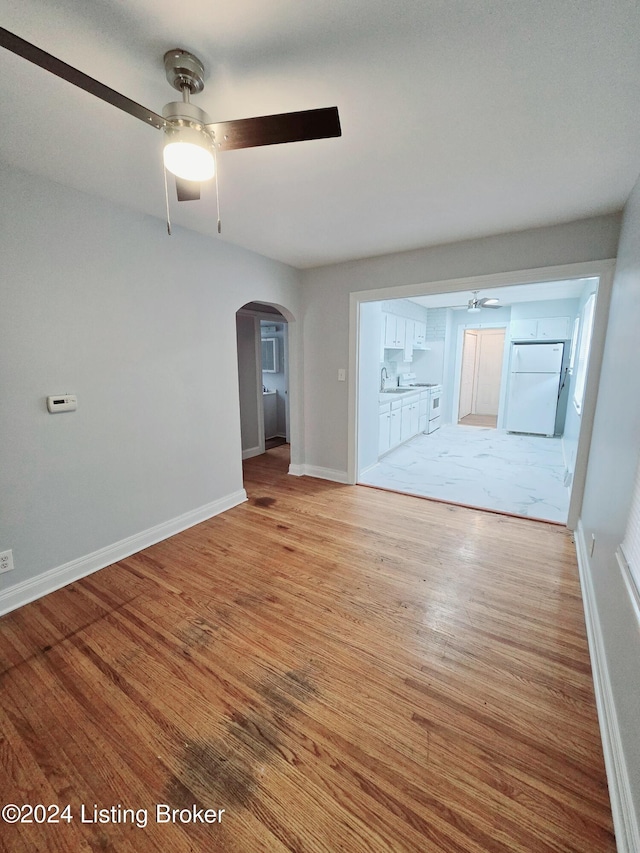 spare room featuring ceiling fan, sink, and light wood-type flooring