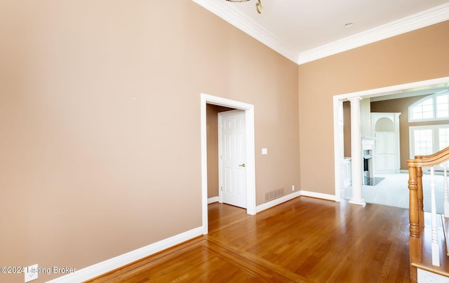 unfurnished room featuring wood-type flooring, decorative columns, and ornamental molding