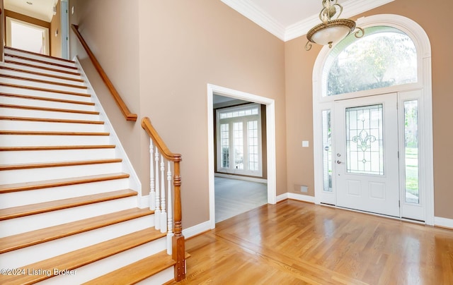 foyer featuring a healthy amount of sunlight, a high ceiling, a chandelier, and light hardwood / wood-style flooring