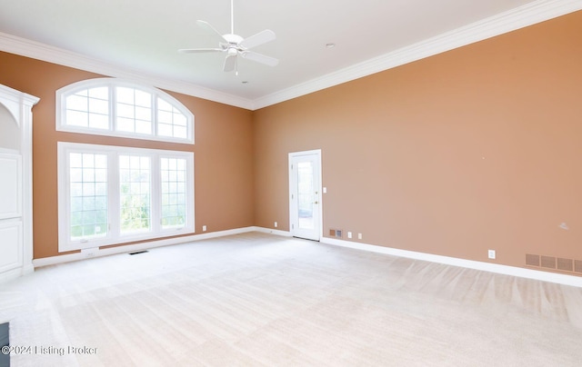 unfurnished room featuring ceiling fan, light colored carpet, ornamental molding, and a high ceiling