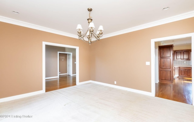 empty room with crown molding, an inviting chandelier, and light hardwood / wood-style flooring