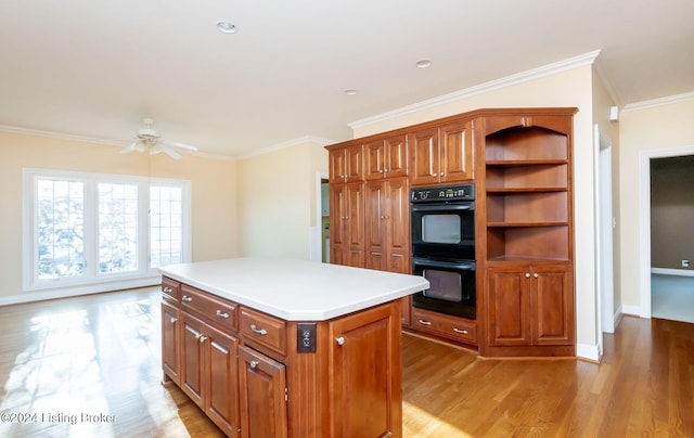 kitchen featuring crown molding, double oven, a center island, and ceiling fan