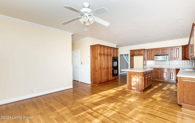 kitchen with wood-type flooring, black appliances, crown molding, a center island, and ceiling fan