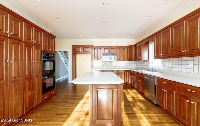 kitchen with tasteful backsplash, a kitchen island, black appliances, hardwood / wood-style flooring, and ornamental molding