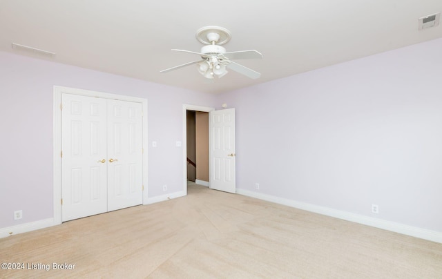 unfurnished bedroom featuring ceiling fan, light colored carpet, and a closet