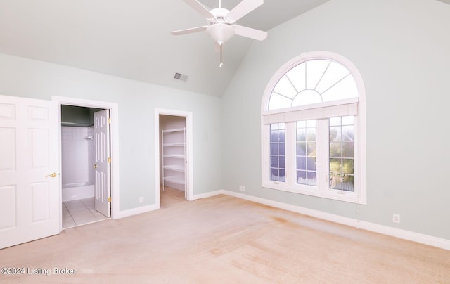 unfurnished bedroom with a spacious closet, a closet, ceiling fan, ensuite bath, and light colored carpet