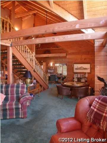 living room featuring carpet flooring, high vaulted ceiling, stairway, and wooden walls