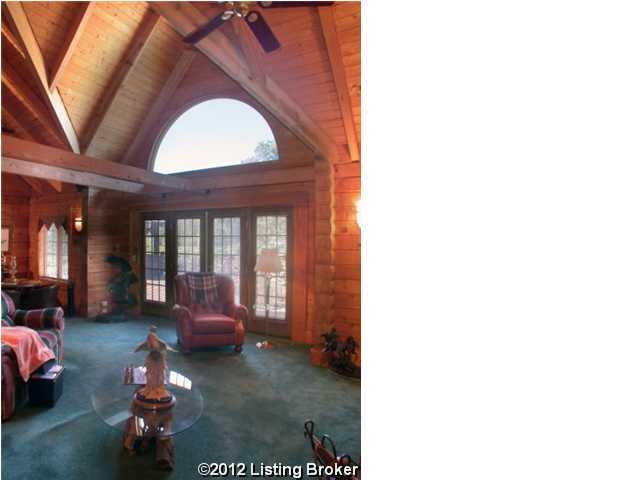 unfurnished living room with ceiling fan, wooden walls, dark colored carpet, and wooden ceiling