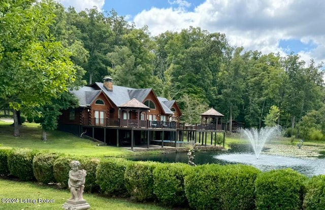 exterior space with a lawn, a deck with water view, and a gazebo