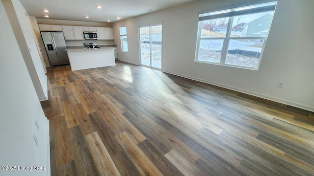 unfurnished living room with baseboards, recessed lighting, and dark wood-style flooring