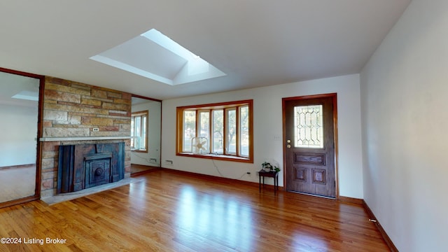 unfurnished living room with lofted ceiling with skylight, a fireplace, and wood-type flooring