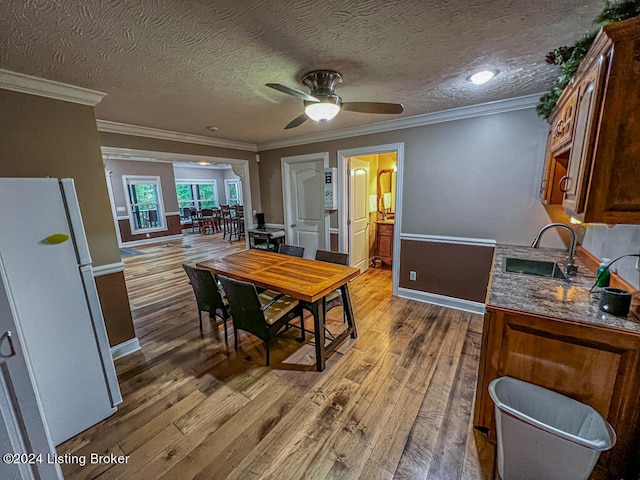 dining space featuring ornamental molding, ceiling fan, hardwood / wood-style floors, and sink