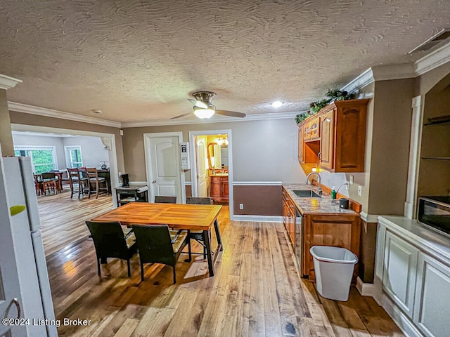 dining room featuring a textured ceiling, sink, light hardwood / wood-style flooring, crown molding, and ceiling fan