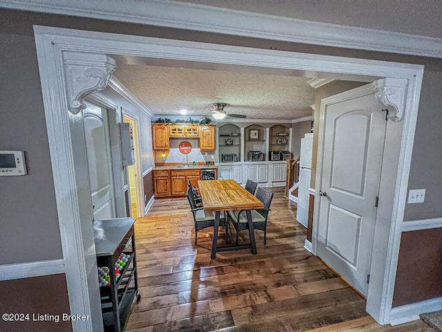 dining space with ornamental molding, ceiling fan, hardwood / wood-style flooring, and a textured ceiling