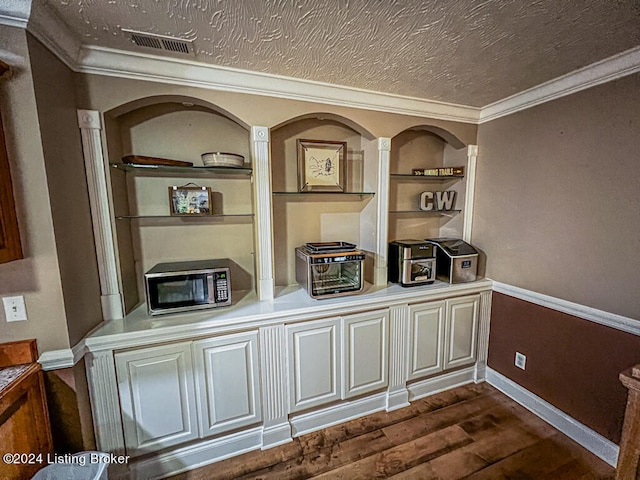 interior details with hardwood / wood-style flooring, crown molding, a textured ceiling, and built in features