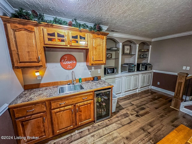 kitchen with wine cooler, a textured ceiling, ornamental molding, dark hardwood / wood-style floors, and sink