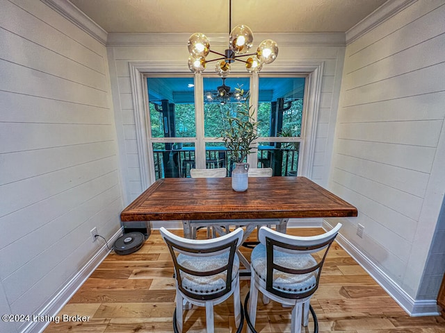 unfurnished dining area with ornamental molding, a chandelier, and light hardwood / wood-style floors