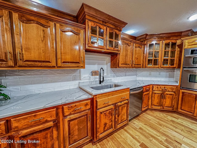 kitchen with light hardwood / wood-style floors, a textured ceiling, tasteful backsplash, sink, and stainless steel appliances