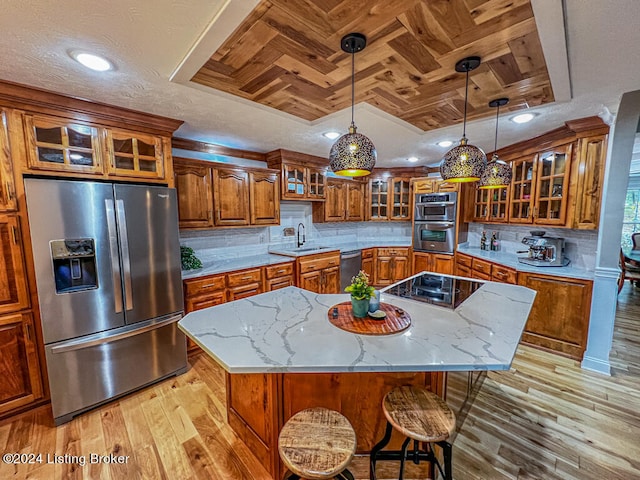 kitchen featuring light wood-type flooring, a kitchen island, stainless steel appliances, and light stone counters