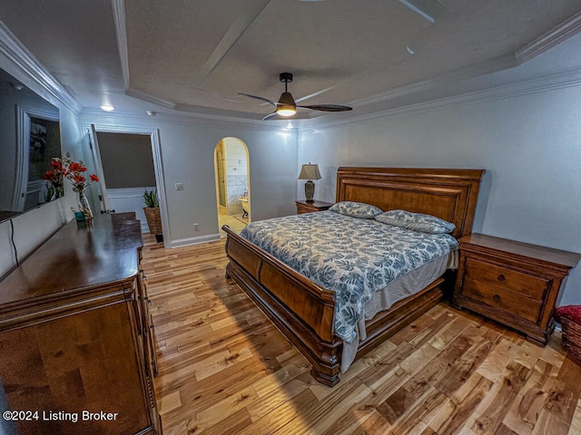 bedroom featuring a tray ceiling, light hardwood / wood-style floors, ensuite bath, ornamental molding, and ceiling fan