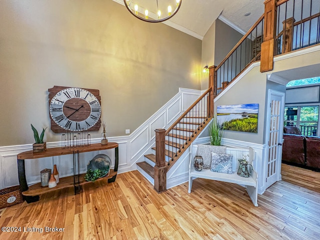 stairway featuring a high ceiling, ornamental molding, an inviting chandelier, and hardwood / wood-style flooring