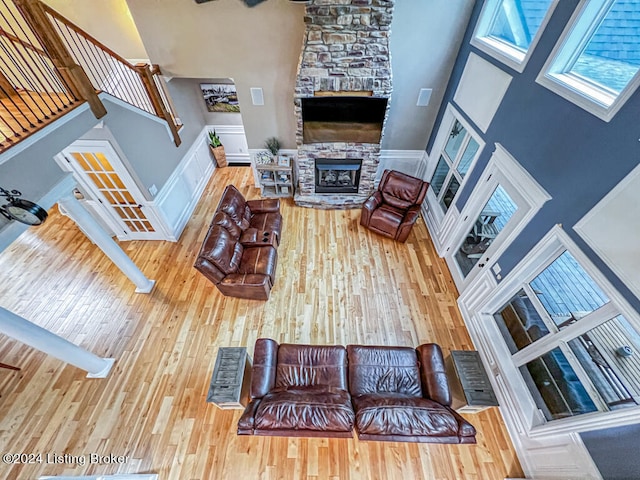 living room featuring wood-type flooring, a high ceiling, a fireplace, and ornate columns