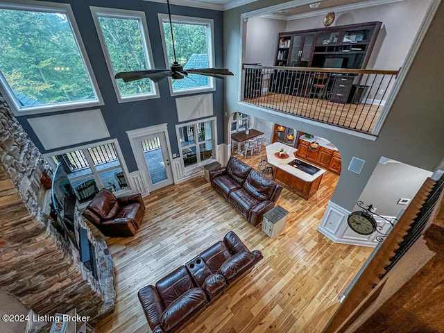 living room with a high ceiling, ornamental molding, ceiling fan, and hardwood / wood-style flooring