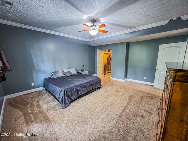 carpeted bedroom featuring a closet, a textured ceiling, ceiling fan, a walk in closet, and ornamental molding