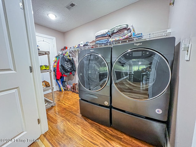 washroom with wood-type flooring, a textured ceiling, and washer and clothes dryer