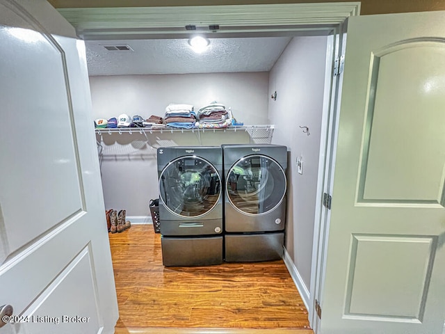 washroom with hardwood / wood-style flooring, independent washer and dryer, and a textured ceiling