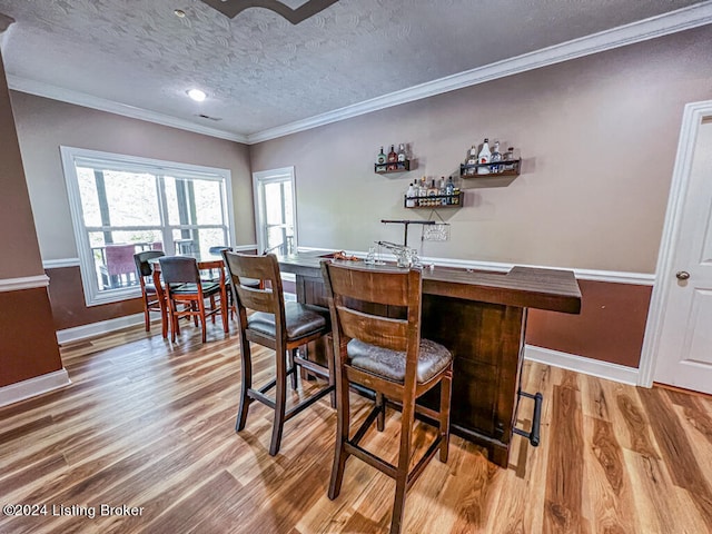 bar with hardwood / wood-style flooring, crown molding, and a textured ceiling