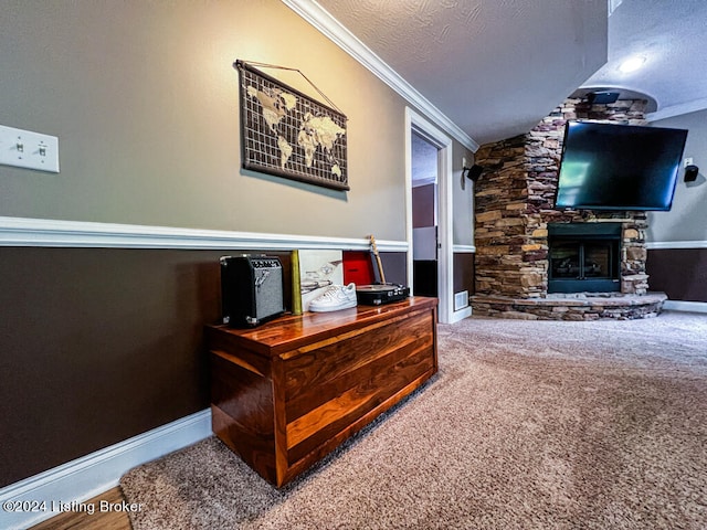 interior space with a stone fireplace, a textured ceiling, and ornamental molding