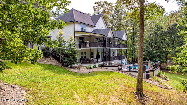 back of property with a balcony, a swimming pool side deck, and a yard