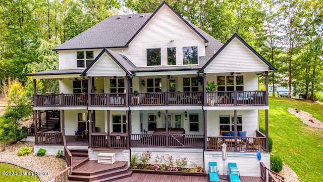 back of house with ceiling fan, a deck, a lawn, and covered porch