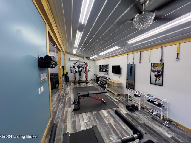 exercise area featuring wood-type flooring, vaulted ceiling, and a wall mounted AC