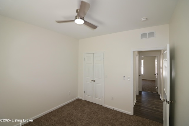 unfurnished bedroom with ceiling fan, a closet, and dark carpet