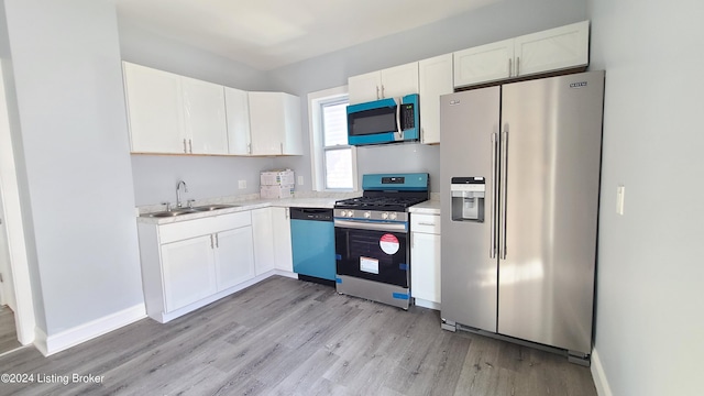 kitchen with white cabinets, stainless steel appliances, sink, and light hardwood / wood-style flooring