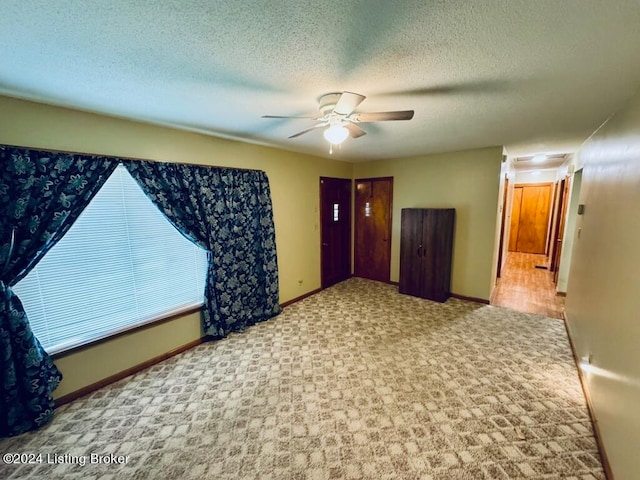 carpeted empty room featuring a textured ceiling and ceiling fan