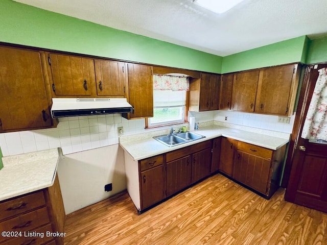 kitchen featuring decorative backsplash, light wood-type flooring, and sink