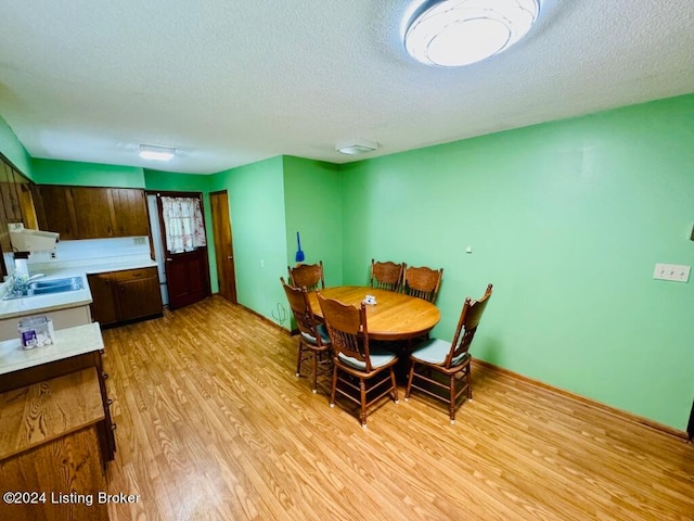 dining room with a textured ceiling, light hardwood / wood-style floors, and sink