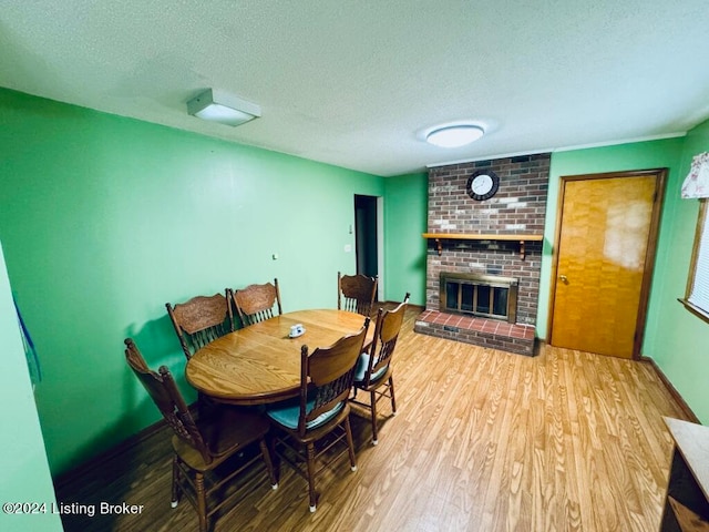 dining space with hardwood / wood-style flooring, a fireplace, and a textured ceiling