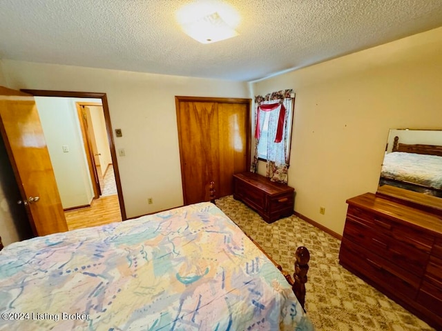 carpeted bedroom featuring a textured ceiling and a closet