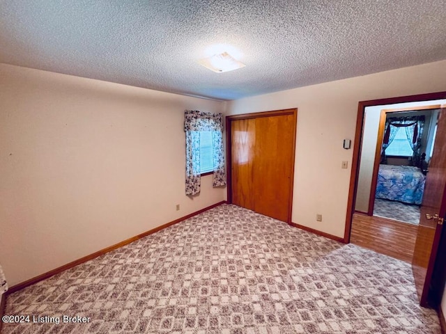 unfurnished bedroom featuring a textured ceiling, light colored carpet, and a closet