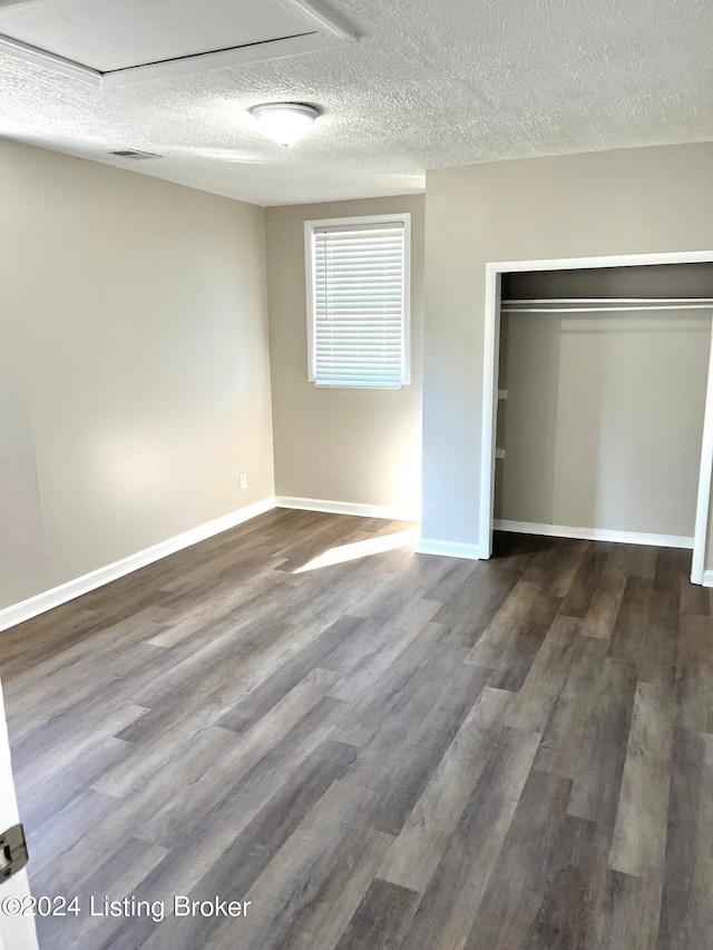 unfurnished bedroom featuring a textured ceiling, a closet, and dark hardwood / wood-style floors