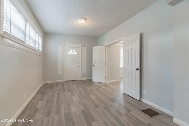 foyer entrance with a textured ceiling and light hardwood / wood-style floors