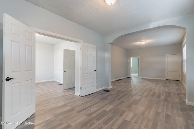 spare room with a textured ceiling and hardwood / wood-style floors