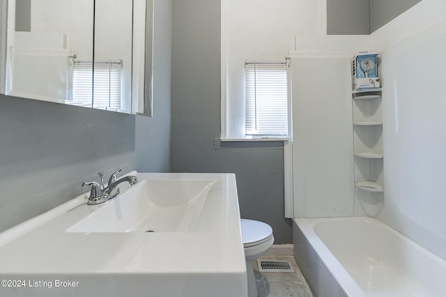 bathroom featuring vanity, a tub to relax in, tile patterned flooring, and toilet