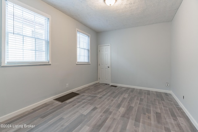 empty room with wood-type flooring and a textured ceiling