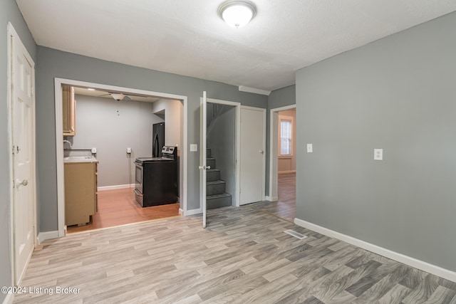 unfurnished bedroom featuring a closet, light hardwood / wood-style floors, black refrigerator, and sink